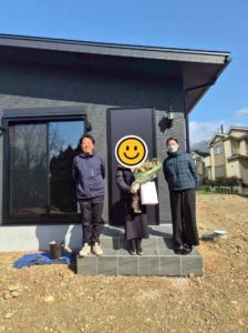 滋賀県で建てたスタイリッシュな黒い外壁の平屋のお引渡し式。施主様とスタッフの記念写真。