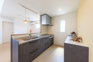 滋賀の平屋、モダンなグレーの対面キッチン。背面の収納棚も完備した、広々として家事がしやすいキッチン空間。